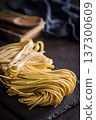 Fresh pasta ready for cooking, showing strands of bigoli set on a black background 137300609