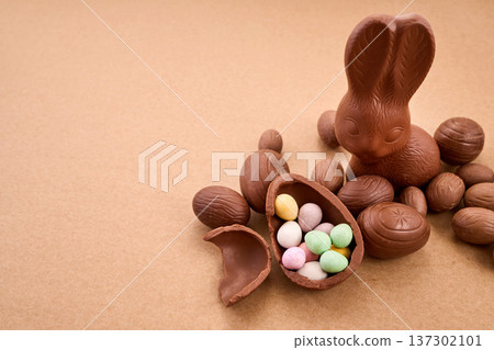 Chocolate easter bunny with candy eggs on brown background Chocolate easter bunny with candy eggs on brown background 137302101