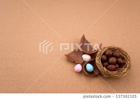 Chocolate easter eggs and nest with candy on brown background Chocolate easter eggs and nest with candy on brown background 137302105
