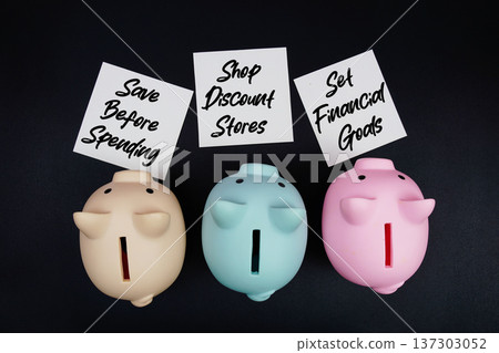 Three piggy banks with sticky note written "Save Before Spending," "Shop Discount Stores," and "Set Financial Goals," financial planning goals on a black background Three piggy banks with sticky note written "Save Before Spending," "Shop Discount Stores," and "Set Financial Goals," financial planning goals on a black background 137303052