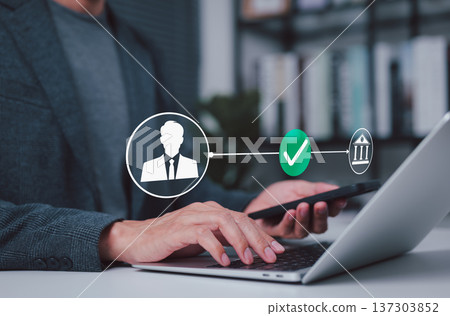 Online banking concept showing secure identity verification and digital transaction approval, with a businessman using laptop and smartphone to authorize bank transfer or financial service access. Online banking concept showing secure identity verification and digital transaction approval, with a businessman using laptop and smartphone to authorize bank transfer or financial service access. 137303852