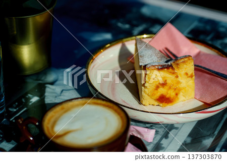Traditional Spanish burnt cheesecake served with cappuccino. Gourmet dessert, morning coffee break and cozy cafe atmosphere. 137303870