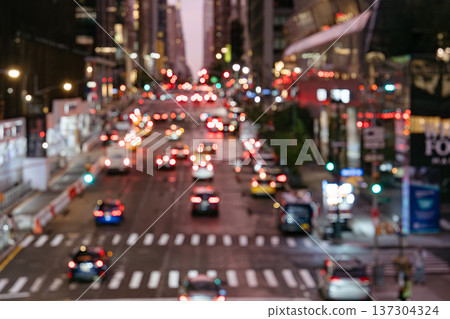 Blurred traffic lights glow along a busy Manhattan street at night. The cityscape captures movement, transportation, and urban energy in New York City. Blurred traffic lights glow along a busy Manhattan street at night. The cityscape captures movement, transportation, and urban energy in New York City. 137304324