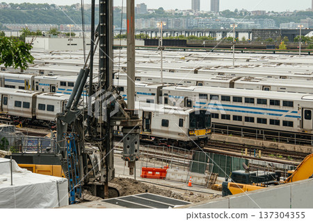 Rows of commuter train cars are parked along multiple tracks in a large Manhattan rail yard. Transportation infrastructure supports daily urban travel across New York City. Rows of commuter train cars are parked along multiple tracks in a large Manhattan rail yard. Transportation infrastructure supports daily urban travel across New York City. 137304355
