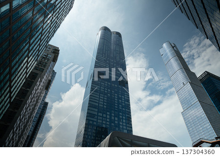 Two tall reflective skyscrapers rise symmetrically into a partly cloudy sky in Manhattan. Contemporary architecture highlights the modern New York City skyline. 137304360