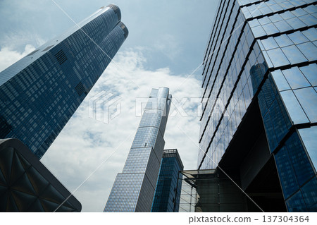 Reflective glass towers rising dramatically into a blue sky in Manhattan, New York City. Contemporary high-rise architecture shapes the urban skyline. 137304364