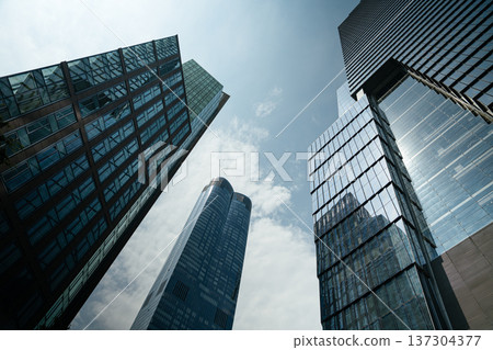 Dramatic low angle view of tall glass skyscrapers rising into the sky in Manhattan, New York City. Modern architecture defines the powerful urban skyline. Dramatic low angle view of tall glass skyscrapers rising into the sky in Manhattan, New York City. Modern architecture defines the powerful urban skyline. 137304377