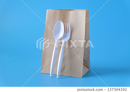 Lunch paper bag with whith fork and spoon on color background. Lunch paper bag with whith fork and spoon on color background. 137304392