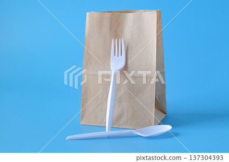 Lunch paper bag with whith fork and spoon on color background. 137304393