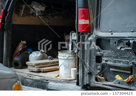 An open work van reveals construction tools, buckets, and materials inside the cargo area. The image represents manual labor, maintenance, and service work. An open work van reveals construction tools, buckets, and materials inside the cargo area. The image represents manual labor, maintenance, and service work. 137304423