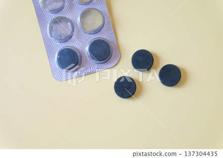 Activated carbon in tablet pill on a light background. Activated carbon in tablet pill on a light background. 137304435