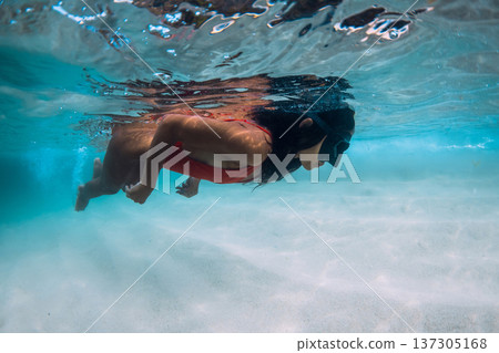 Young woman snorkeling in tropical ocean water, free diving over white sand in turquoise ocean. Young woman snorkeling in tropical ocean water, free diving over white sand in turquoise ocean. 137305168