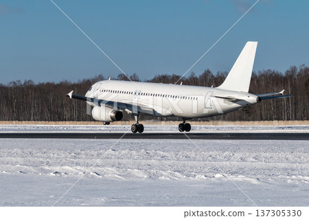 A modern white passenger plane touches the runway at an airport in winter A modern white passenger plane touches the runway at an airport in winter 137305330