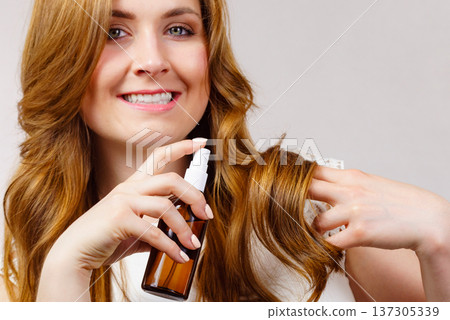 Woman applying hair cosmetic Woman applying hair cosmetic 137305339