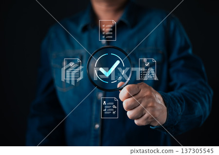 person hold magnifying glass with glowing checkmark surrounded by digital documents and AI icon representing verification,approval,document review,compliance,accuracy,and digital validation processes. 137305545