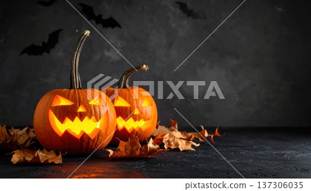 Two glowing carved pumpkins are surrounded by autumn leaves with bats silhouetted against a dark and atmospheric Halloween background scene. 137306035
