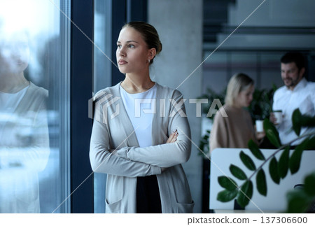 A woman is standing in front of a window with her arms crossed 137306600