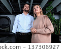 A man and a woman are standing in front of a plant 137306927