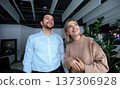 A man and a woman are standing in front of a plant 137306928