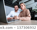 A man and a woman are looking at a laptop together 137306932