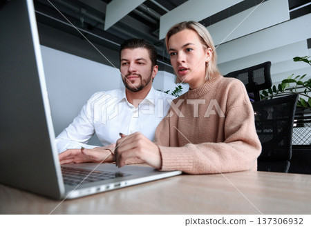 A man and a woman are looking at a laptop together 137306932