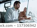 A man and a woman are looking at a computer monitor 137306942