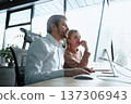 A man and a woman are looking at a computer monitor 137306943