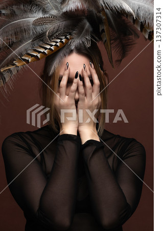 Woman covering face with hands and feather headdress 137307314