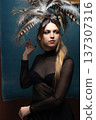 Woman wearing feather headdress and sheer black top 137307316