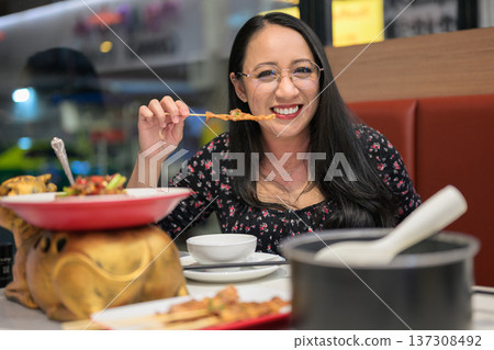 Smiling Woman Eating Grilled Skewer in Asian Restaurant Smiling Woman Eating Grilled Skewer in Asian Restaurant 137308492