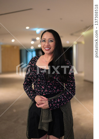 Portrait of smiling Asian woman wearing glasses in contemporary indoor lobby space Portrait of smiling Asian woman wearing glasses in contemporary indoor lobby space 137308518