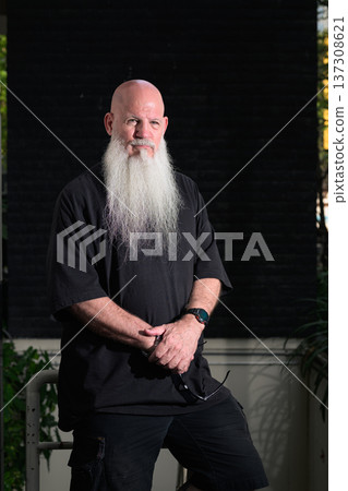Bald Man with Long White Beard Standing Against Dark Wall Bald Man with Long White Beard Standing Against Dark Wall 137308621