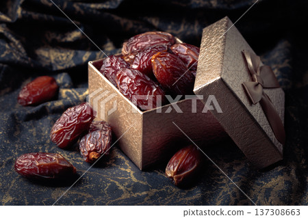 Dates in a gift box on black fabric with gold ornamentation. 137308663