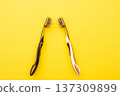 Two personal toothbrushes representing a couple or relationship, placed against a vibrant yellow background, highlighting oral hygiene 137309899