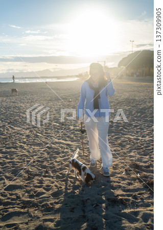 A young woman hugs her Cavalier King Charles Spaniel on the beach at sunset. Warm light, waves, and smiles capture a peaceful, joyful moment of connection and relaxation. A young woman hugs her Cavalier King Charles Spaniel on the beach at sunset. Warm light, waves, and smiles capture a peaceful, joyful moment of connection and relaxation. 137309905