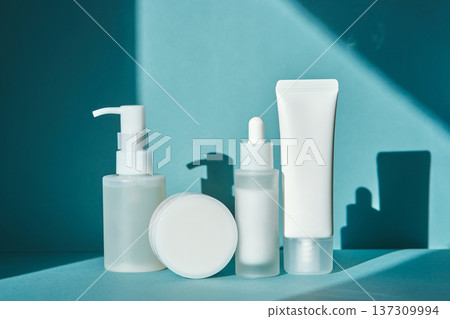 Minimalist skincare cosmetics bottles and tube on blue background Minimalist skincare cosmetics bottles and tube on blue background 137309994