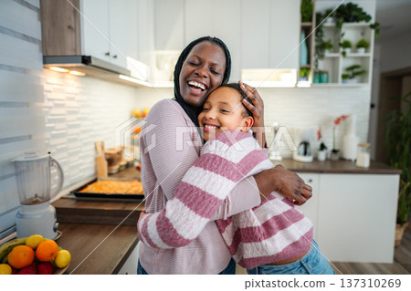 African American mother and daughter embracing in kitchen 137310269