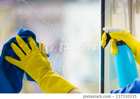 Gloved hand cleaning window rag and spray Gloved hand cleaning window rag and spray 137310335