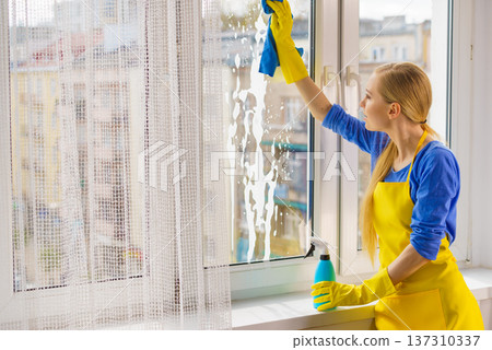 Woman cleaning window at home 137310337