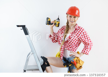 Woman wearing helmet using drill 137310357