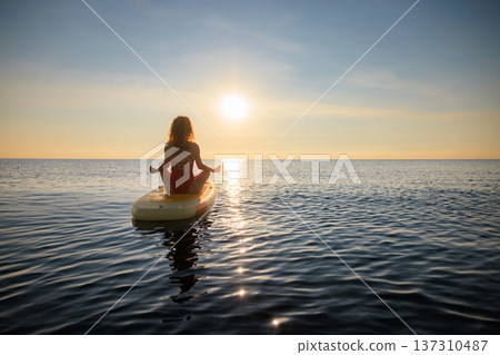 Young woman walking on stand up paddle sup boards by the sea during summer vacation Young woman walking on stand up paddle sup boards by the sea during summer vacation 137310487