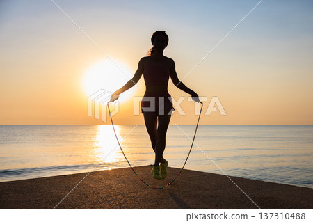 Fit woman jumping rope at the beach during summer vacation Fit woman jumping rope at the beach during summer vacation 137310488