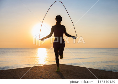 Fit woman jumping rope at the beach during summer vacation 137310489
