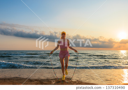 Fit woman jumping rope at the beach during summer vacation Fit woman jumping rope at the beach during summer vacation 137310490