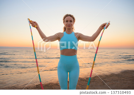 Fit woman jumping rope at the beach during vacation. Healthy lifestyle and summer sport concept Fit woman jumping rope at the beach during vacation. Healthy lifestyle and summer sport concept 137310493