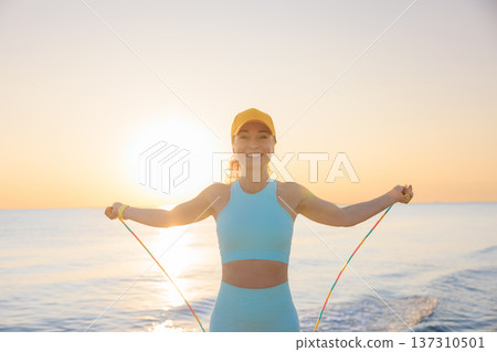 Fit woman jumping rope at the beach during summer vacation 137310501