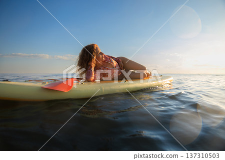 Young woman walking on sup board by the sea during summer vacation 137310503