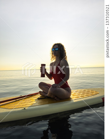 Young woman walking on stand up paddle sup boards by the sea during summer vacation Young woman walking on stand up paddle sup boards by the sea during summer vacation 137310521