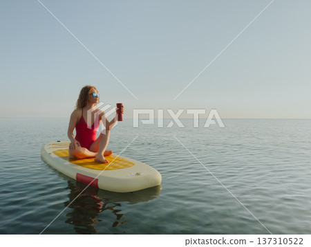 Young woman walking on stand up paddle sup boards by the sea during summer vacation Young woman walking on stand up paddle sup boards by the sea during summer vacation 137310522