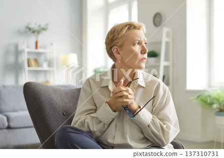 Portrait of mature elderly woman wearing casual clothes looking to the side sitting at home. Portrait of mature elderly woman wearing casual clothes looking to the side sitting at home. 137310731